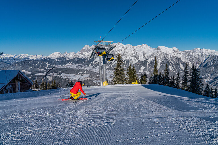 Skiers with Planai main gondola and Dachstein panorama | © Christine Höflehner