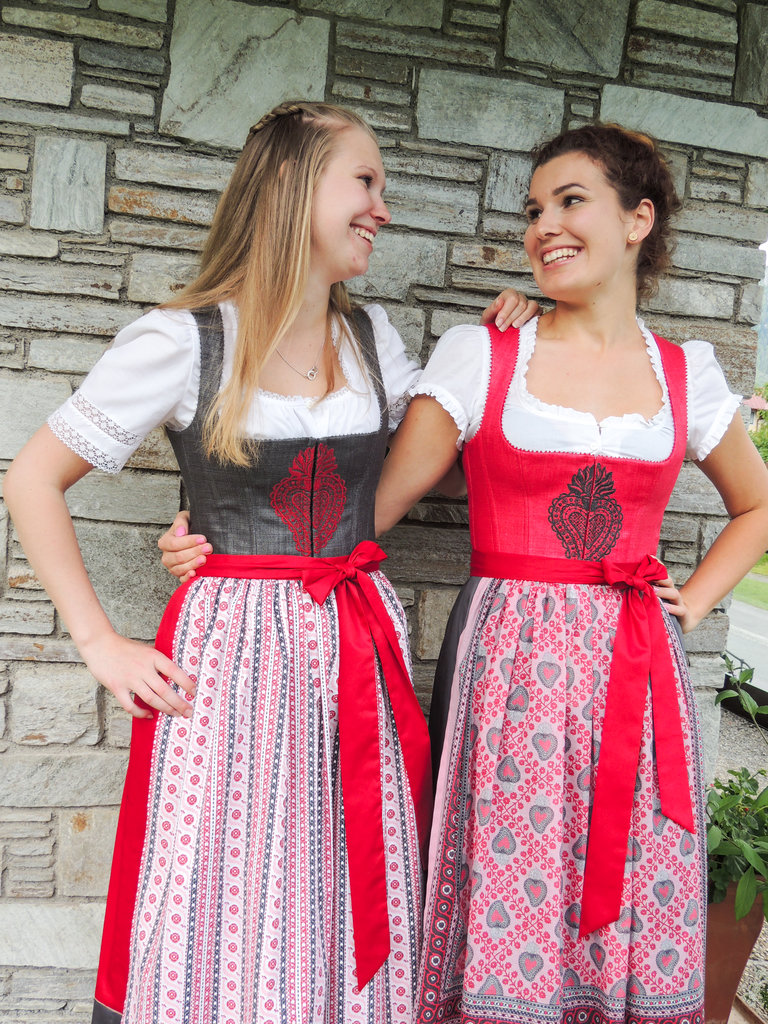 Zwei Frauen im roten dirndl mit besticktem Leib. | © Sportmoden Schrempf