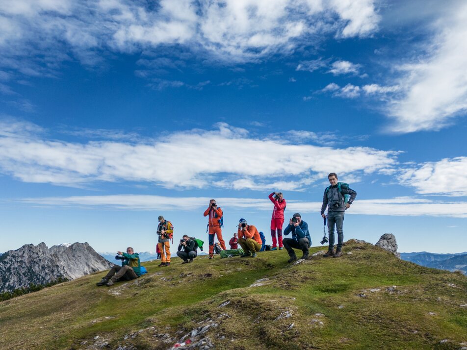 Gruppe von Bergwanderern und Fotografen posiert auf einem Gipfel mit Alpenpanorama. | © Oliver Richter Leica