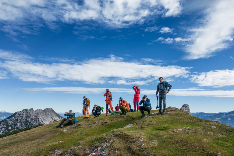 Gruppe von Bergwanderern und Fotografen posiert auf einem Gipfel mit Alpenpanorama. | © Oliver Richter Leica